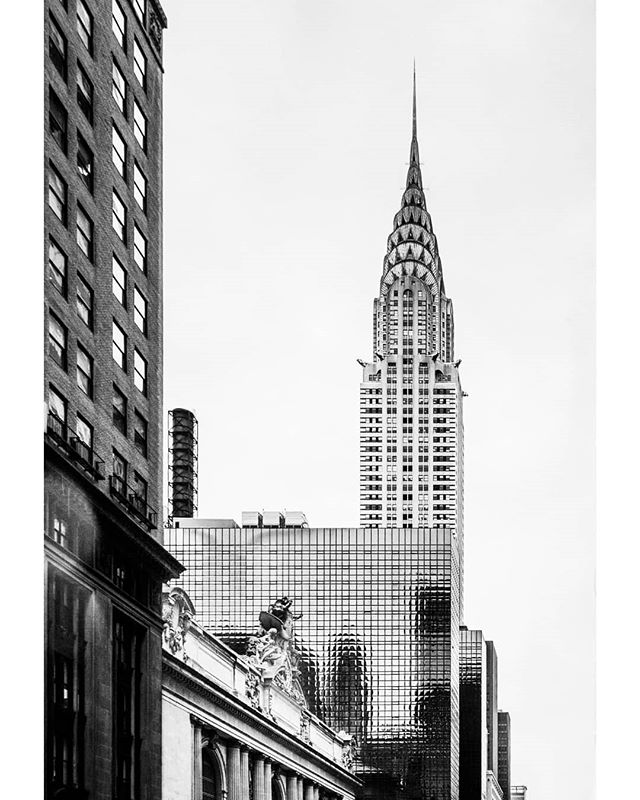 A monochrome view of the iconic Chrysler Building, framed by surrounding architecture in New York City.