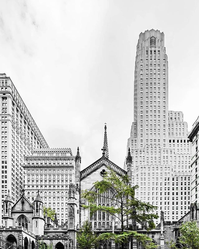 A black and white image features a church surrounded by tall buildings, showcasing the city's architecture.