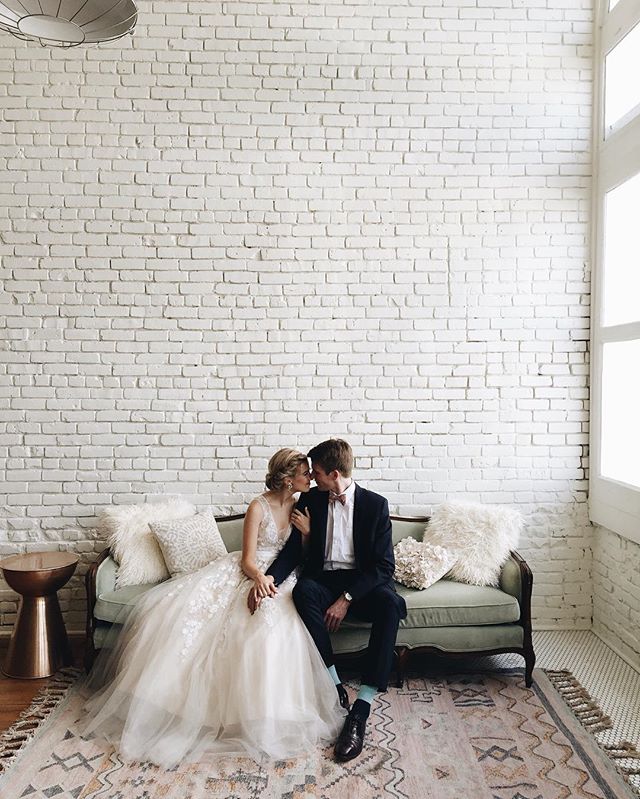 A bride and groom share an intimate moment on a vintage couch after their wedding.