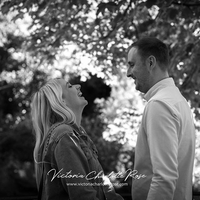 A happy couple shares a loving moment outdoors, laughing together in a candid black and white shot.