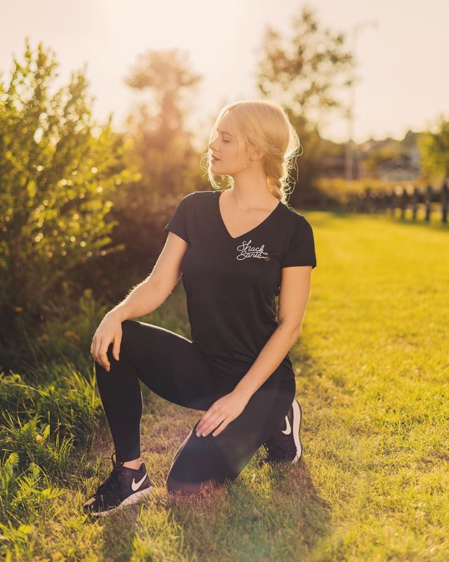 A woman in athletic wear poses in a park during a golden hour workout.