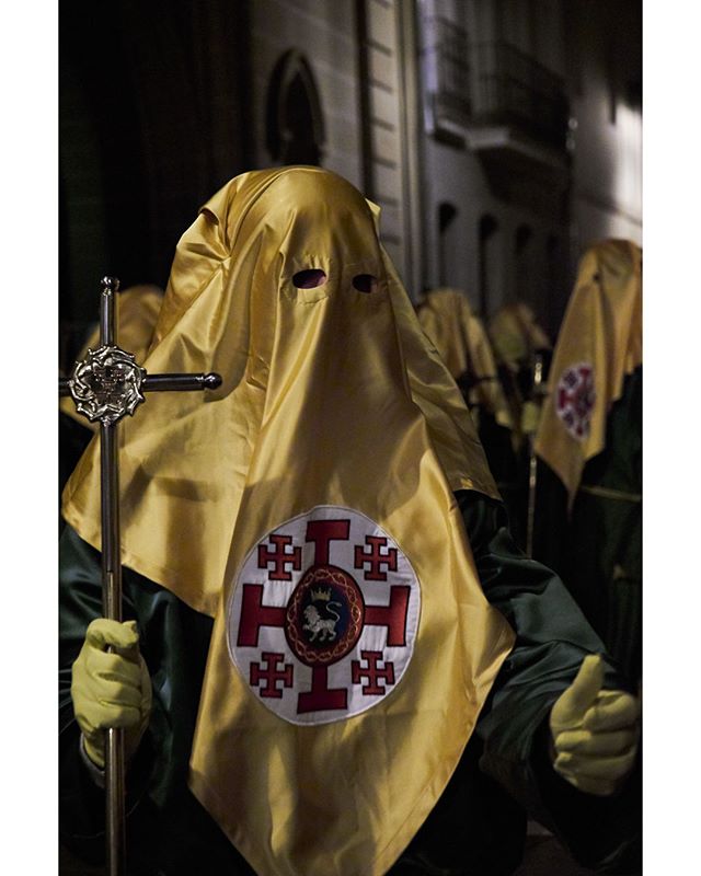 Figures in hooded robes participate in a solemn night procession, symbolizing religious tradition and cultural heritage.