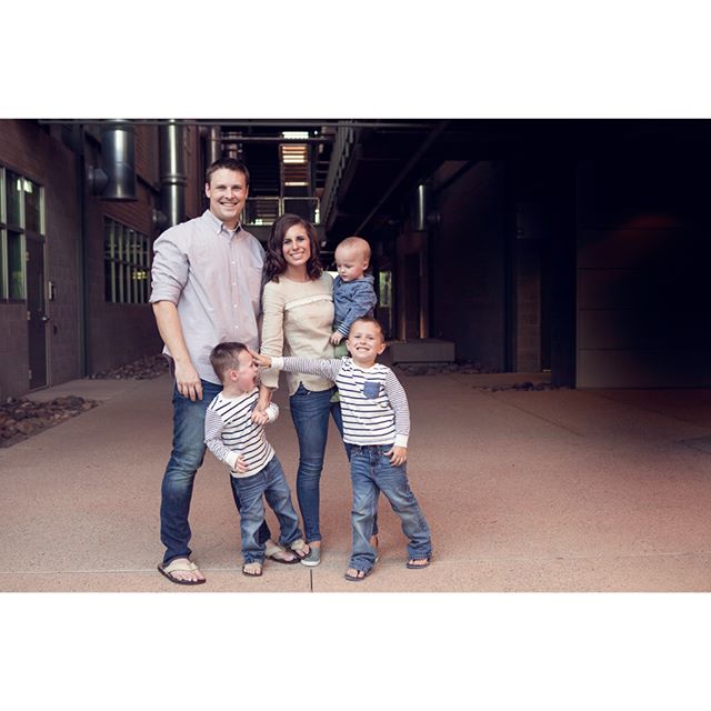 A happy family of five poses outdoors in an urban setting, smiling and enjoying quality time together.