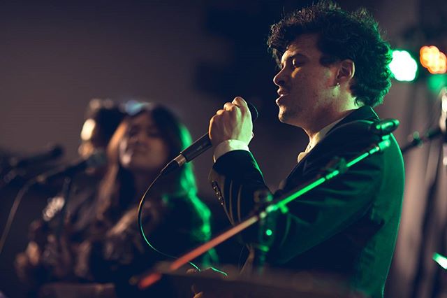 A singer performs live on stage with a microphone during a musical event.