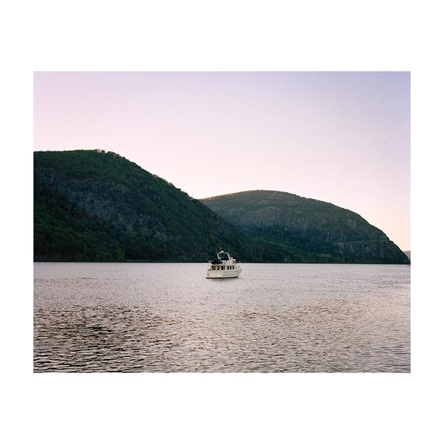 A boat sails on a tranquil lake surrounded by mountains on a calm day.