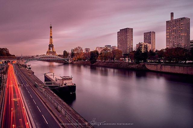 The Eiffel Tower and city buildings line the Seine River in Paris in this scenic, long exposure cityscape.