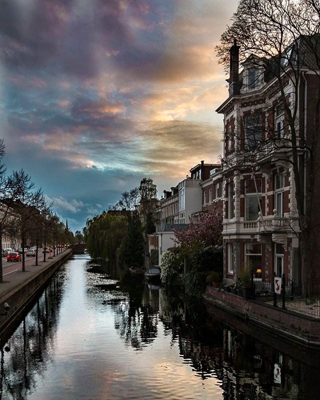 Scenic view of buildings along a calm canal under a colorful sky, perfect for travel and tourism marketing.