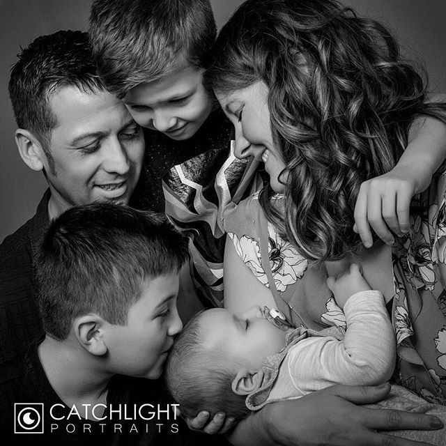 A family of five is captured in a loving embrace in this black and white portrait.