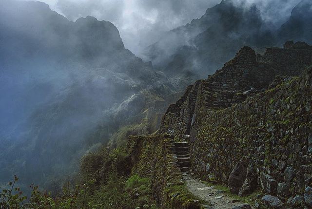 Misty mountains and ancient stone walls evoke a sense of adventure at Machu Picchu, Peru.