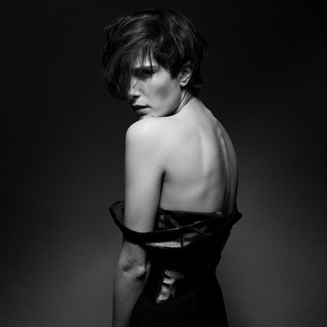 Black and white studio shot of a woman with short hair looking over her shoulder with soft, dramatic lighting.