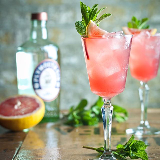 Refreshing grapefruit cocktail with mint garnish on a wooden table, perfect for social media advertising.