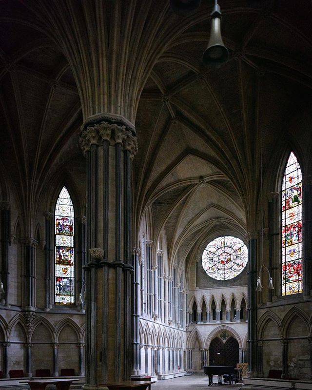 The serene interior of a gothic cathedral with high arches and stained glass windows evokes a sense of history and peace.