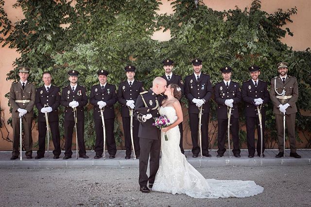 Bride and groom kissing surrounded by police officers in uniform at their wedding.