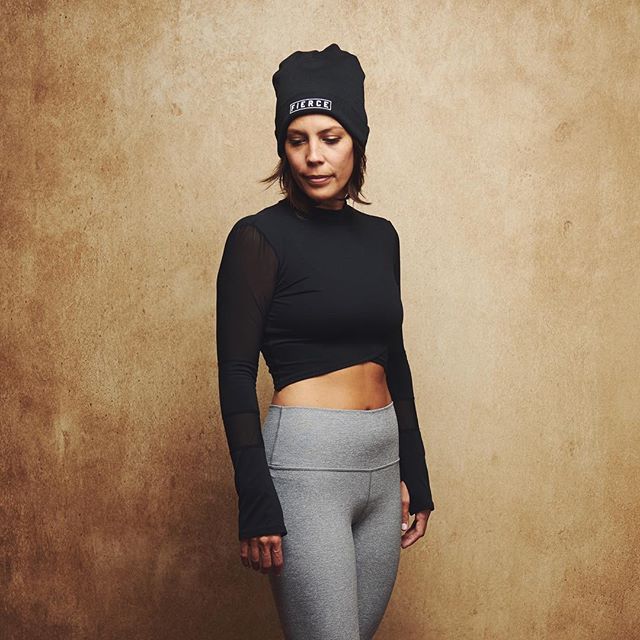 A woman in workout attire strikes a pose against a neutral backdrop, promoting fitness and an active lifestyle.