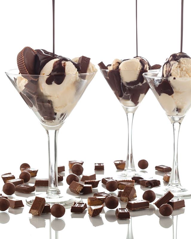 Three ice cream sundaes with chocolate sauce and candy pieces scattered around, creating an enticing and visually appealing dessert composition.