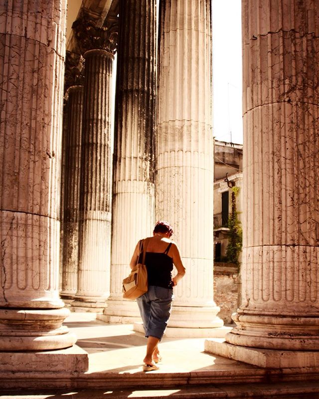 A woman walks among the ancient columns, capturing the essence of history and travel in a serene outdoor setting.
