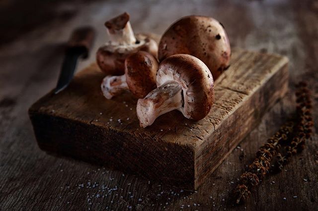 Still life of brown mushrooms on a wooden board with a knife for culinary or stock photography.