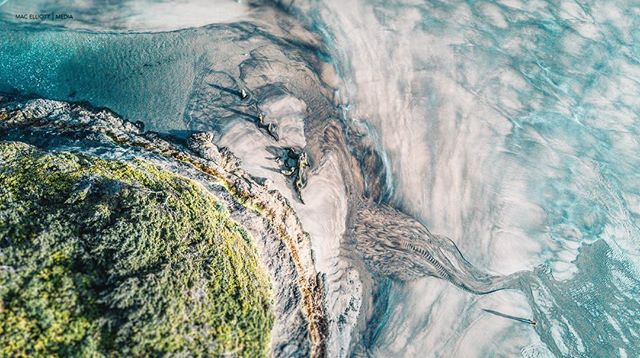 Aerial view of a stunning shoreline with sand patterns and clear ocean water, creating a tranquil and scenic landscape.