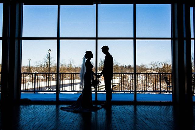 Silhouette of a bride and groom holding hands in front of a window. Represents love and new beginnings.