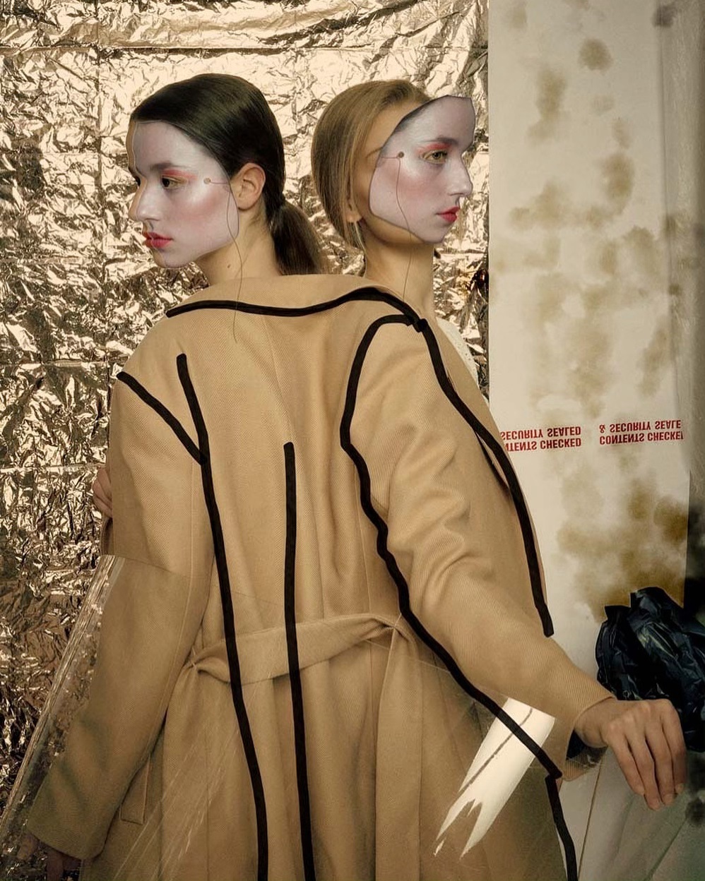 Two women pose in avant-garde fashion in a studio setting for an editorial photoshoot, showcasing futuristic and artistic styles.