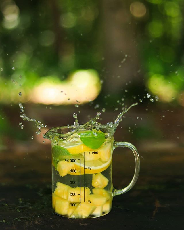 A refreshing fruit drink with splashing water adds a lively touch to a garden setting.