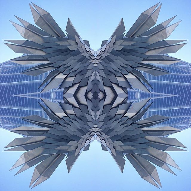 Abstract architectural design featuring geometric shapes against a clear blue sky, creating a modern urban landscape.