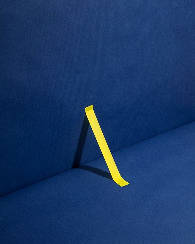 Yellow tape stands against a textured blue backdrop, capturing a minimalist, modern aesthetic.