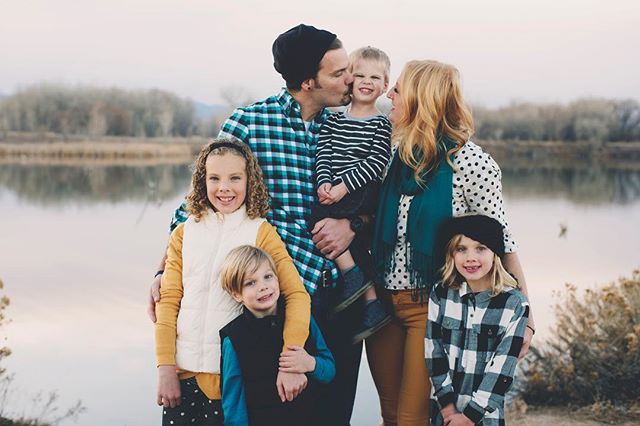 A family of six stands by a lake in a candid, happy moment.