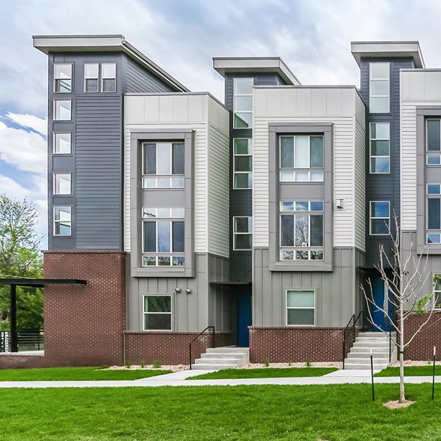 Modern townhouses with clean lines and neutral colors, set in an urban neighborhood with well-maintained green spaces.