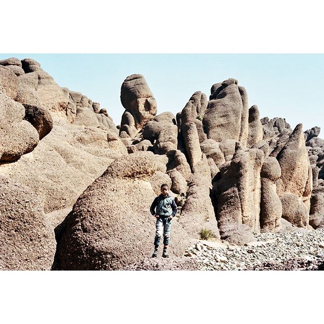 A man stands among unique rock formations in a desert landscape, embodying adventure and exploration.