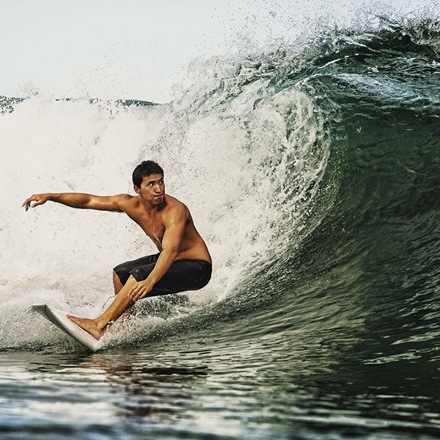 A surfer rides a large wave in the ocean, showcasing fitness and an active lifestyle.