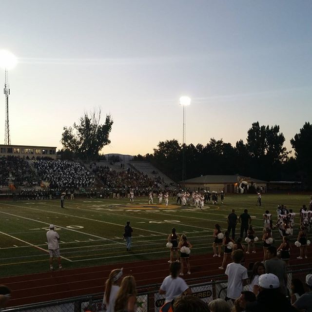 A lively football game at a stadium filled with enthusiastic spectators and cheerleaders.