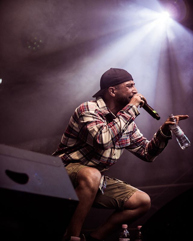 A male singer performs on stage with a microphone and water bottle during a concert.