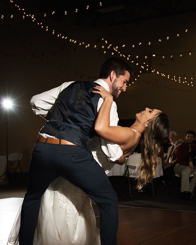 A bride and groom share their first dance at their wedding reception under string lights.