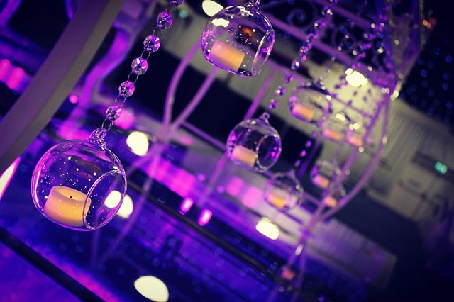 Elegant glass orbs with candles hang amidst soft purple lighting, creating a dreamy and intimate atmosphere for a special event.