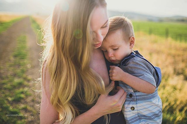 A mother lovingly holds her sleeping child in a peaceful outdoor setting.  A moment of connection and care.
