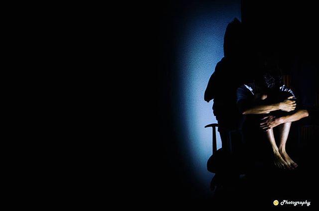 A silhouetted figure sits alone in a dimly lit room, evoking feelings of isolation and contemplation.