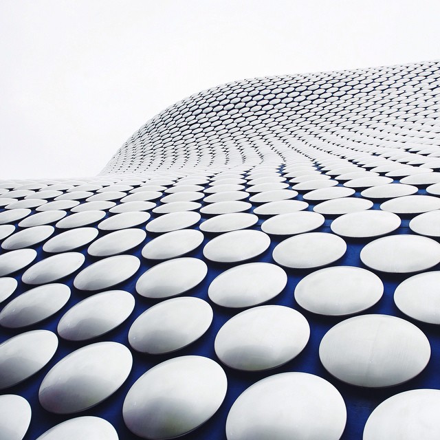 Abstract architectural detail featuring a modern building facade with a repeating pattern of white discs against a blue background.