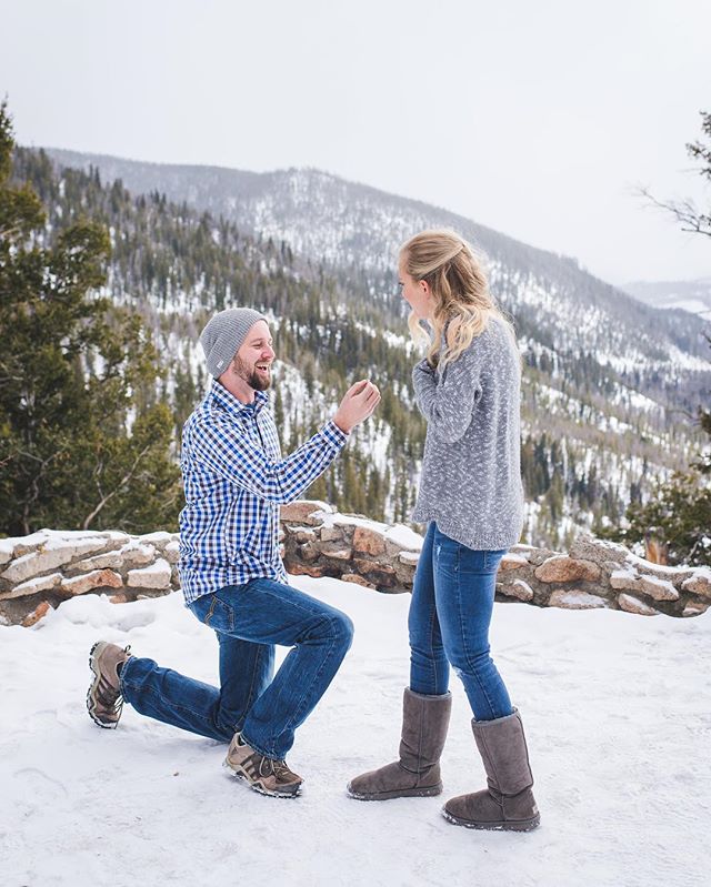 A man proposes to a woman in a snowy mountain landscape, capturing a moment of love and commitment.