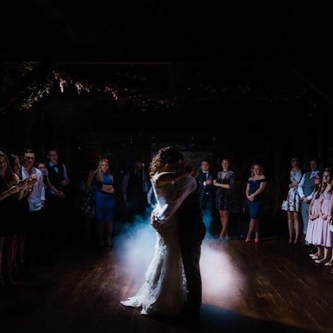 A bride and groom share their first dance at their wedding reception, surrounded by family and friends.