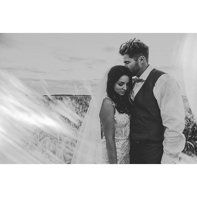 A bride and groom share a tender moment in a black and white wedding photo.