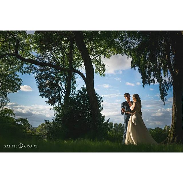 A bride and groom share a tender moment outdoors on their wedding day in a romantic park setting.