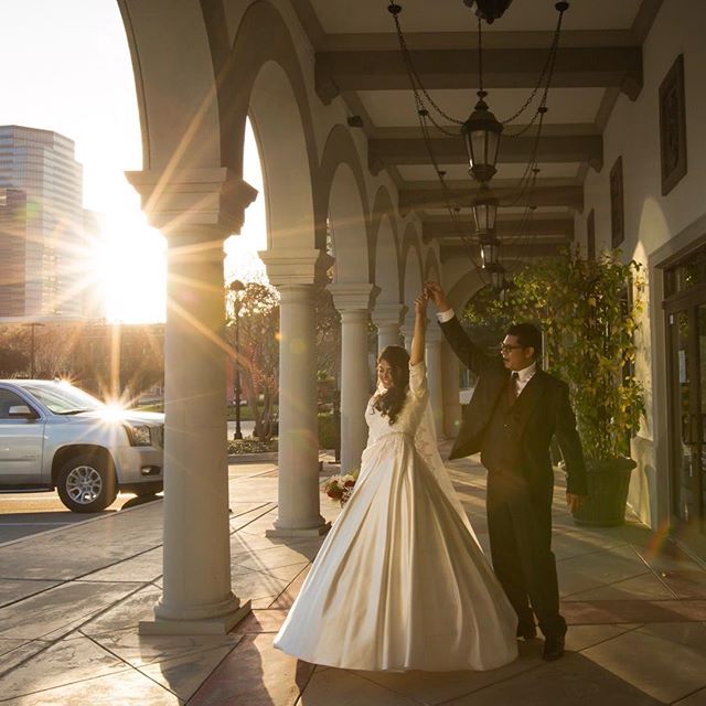 A bride and groom joyfully celebrate their wedding day under an archway as the sun sets, symbolizing new beginnings.