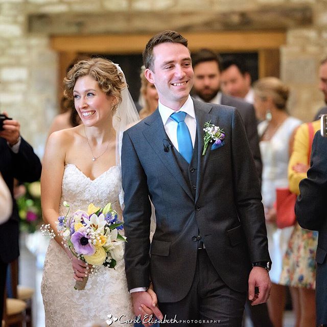 A bride and groom smile happily as they walk down the aisle after their wedding ceremony.