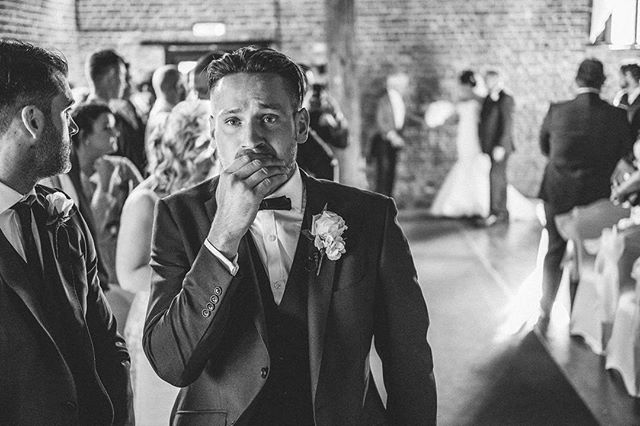 A groom overcome with emotion during a wedding ceremony, captured in a candid, black and white image.