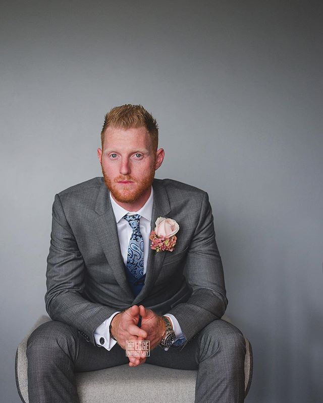 A man in a gray suit poses formally, likely for a wedding or special event.