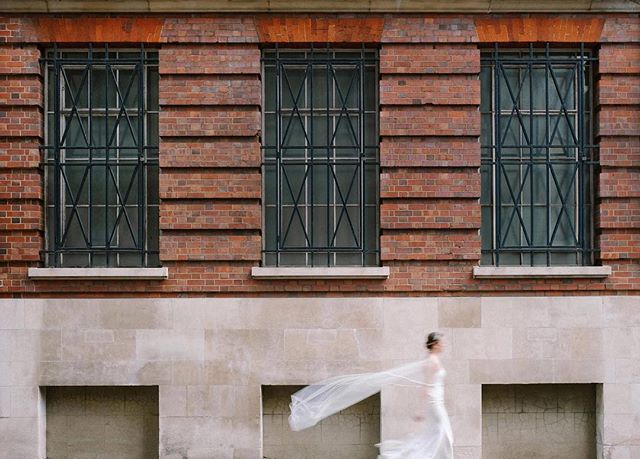 A bride in a white dress and veil walks along a city street, creating a dreamy and romantic moment.