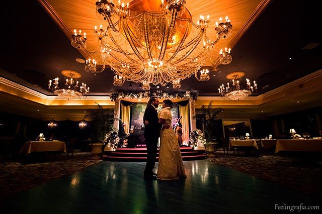 A bride and groom share a loving moment under a grand chandelier during their wedding reception.