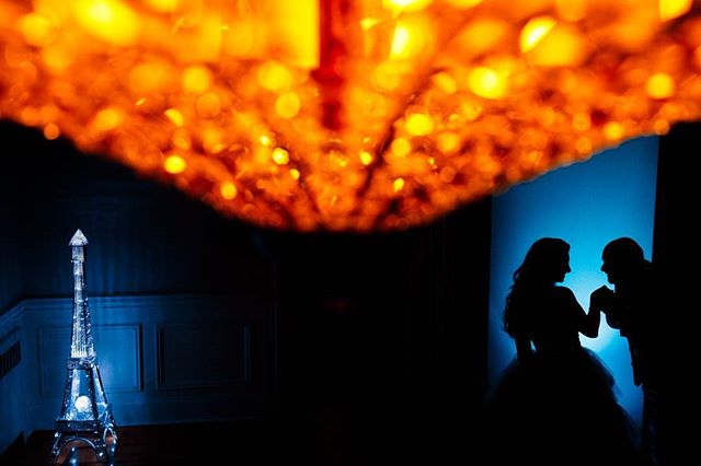 Silhouetted couple with an Eiffel Tower model and chandelier creating a romantic and dreamy ambiance.