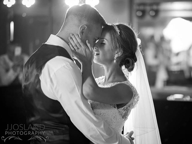 A bride and groom share a tender moment during their first dance in black and white.